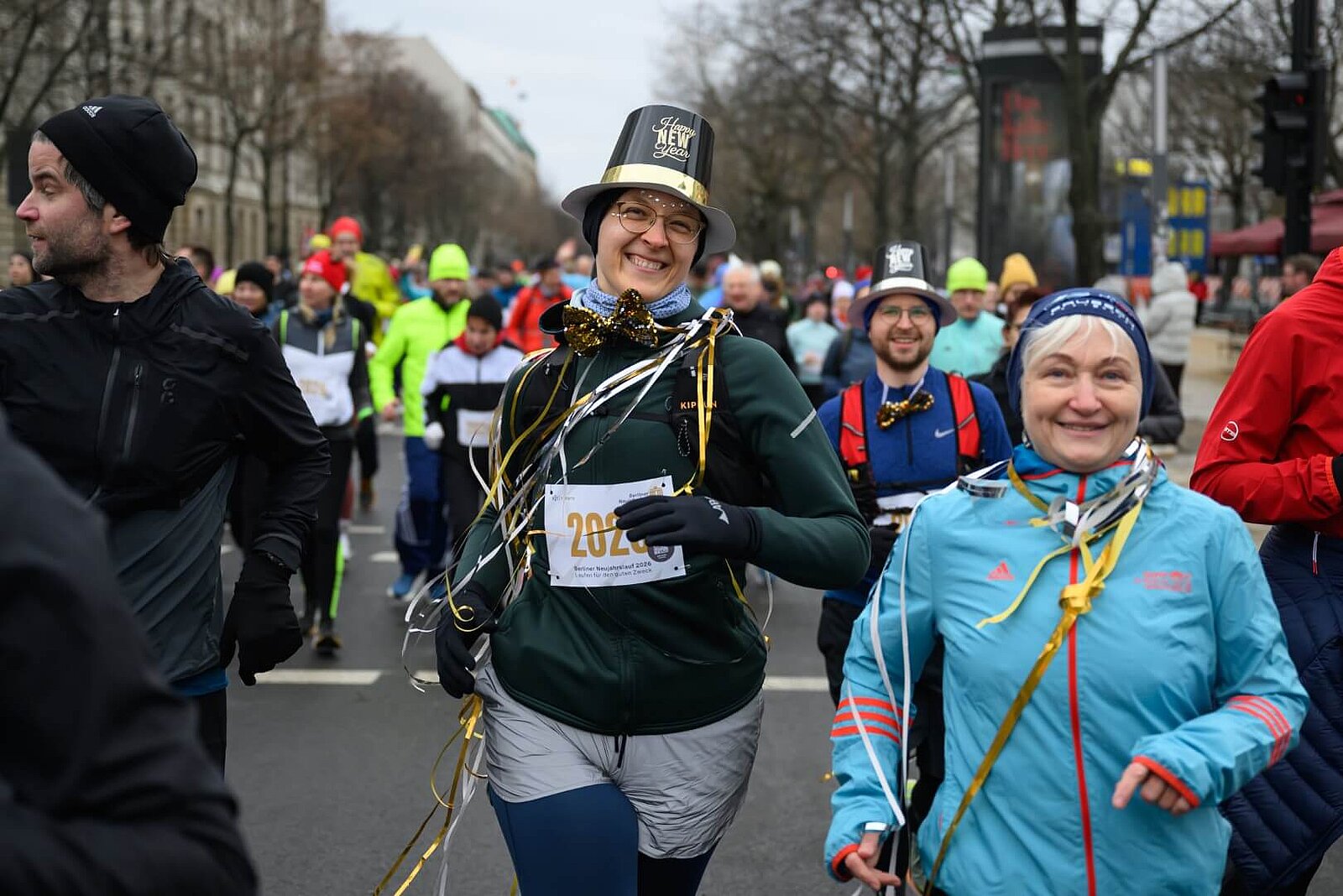 Zwei Läuferinnen mit Luftschlangen um den Hals. Die rechte trägt einen Partyhut.