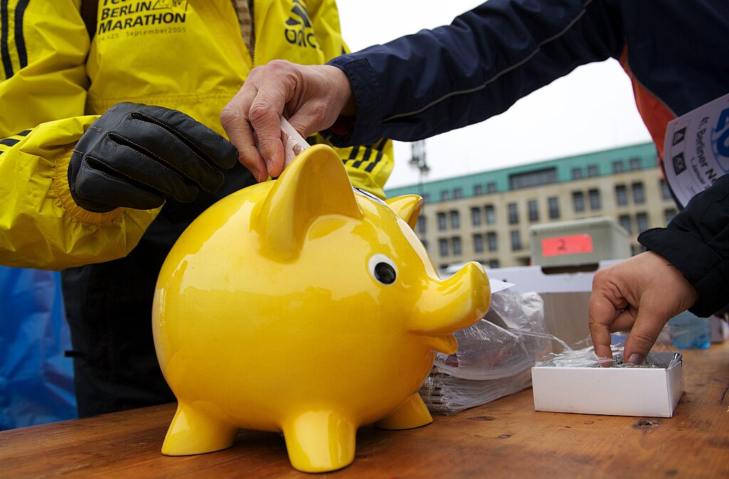 Gelbes Sparschwein wird mit einem 10 Euro Schein gefüttert © SCC EVENTS / camera4