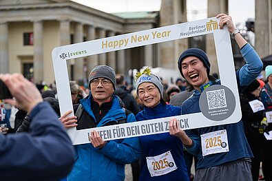 Drei Läufer:innen freuen sich über ein Bild mit dem Rahmen